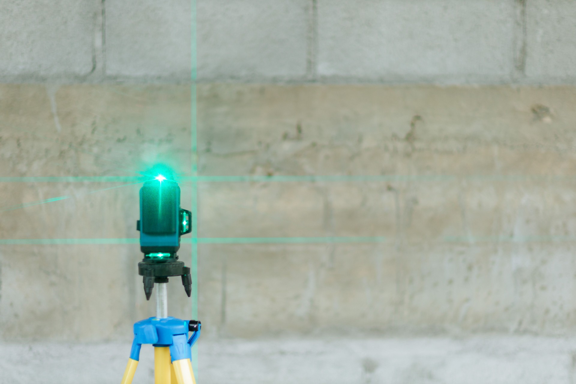 Construction worker is using cross-line laser level meter with line green beam to mark the floor in construction site. Tools for measuring distances. the builder measures the repair lines using a green laser level,